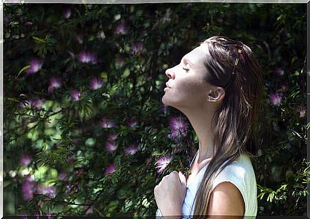 a woman tries a breathing exercise under a tree