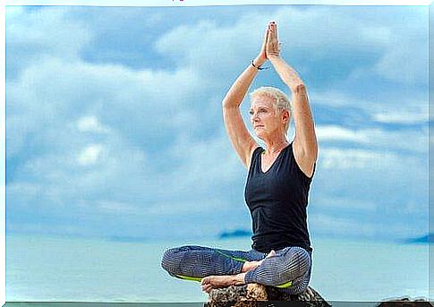 senior woman practicing yoga on the beach